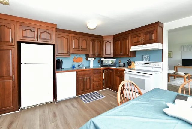 a kitchen with stainless steel appliances granite countertop a refrigerator a stove a sink dishwasher and white countertops with wooden floor