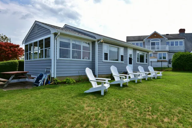 a front view of a house with a garden and chairs