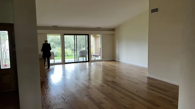a view of an empty room with wooden floor and a window