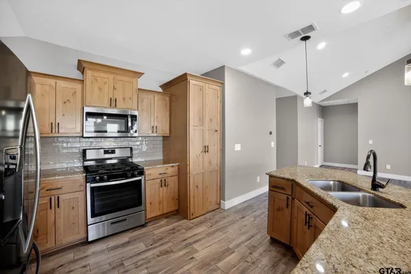 a kitchen with stainless steel appliances granite countertop a sink stove and refrigerator