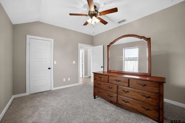 a room that has a dresser and a chandelier fan