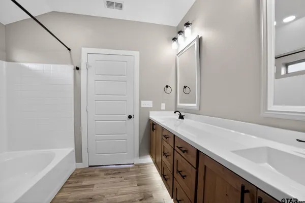 a spacious bathroom with a tub sink and mirror