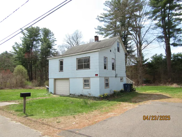 a view of a white house with a big yard and large tree