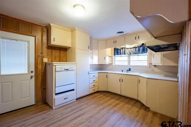 a kitchen with wooden floors and white cabinets