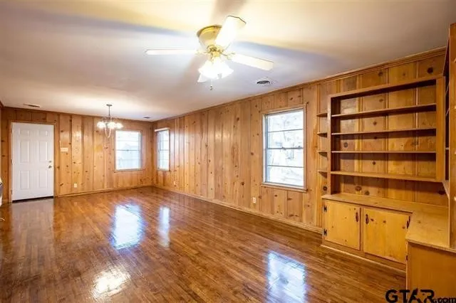 a view of an empty room with window and wooden floor