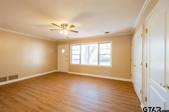 an empty room with wooden floor and windows