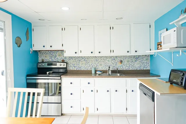 a kitchen with granite countertop white cabinets and stainless steel appliances