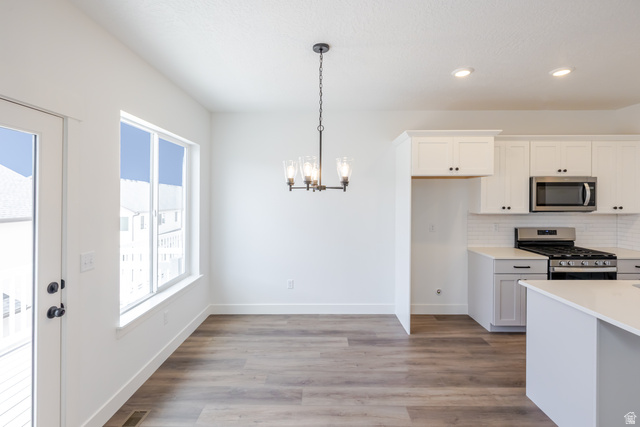 4812 Heartwood Road, Unit 424 Mapleton, UT 84664 - Photo 7 of 20 Kitchen featuring white cabinetry, stainless steel appliances, light wood-type flooring, a chandelier, and tasteful backsplash