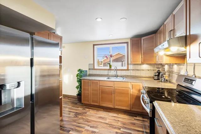 a kitchen with stainless steel appliances granite countertop a refrigerator a sink a stove and island