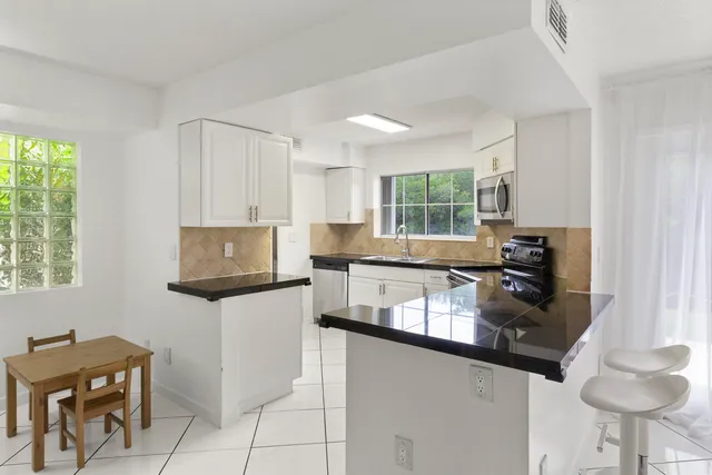 a kitchen with kitchen island granite countertop a sink stove and microwave