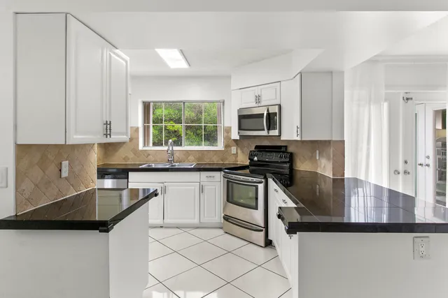 a kitchen with granite countertop a stove sink and cabinets