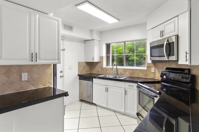a kitchen with granite countertop white cabinets and appliances