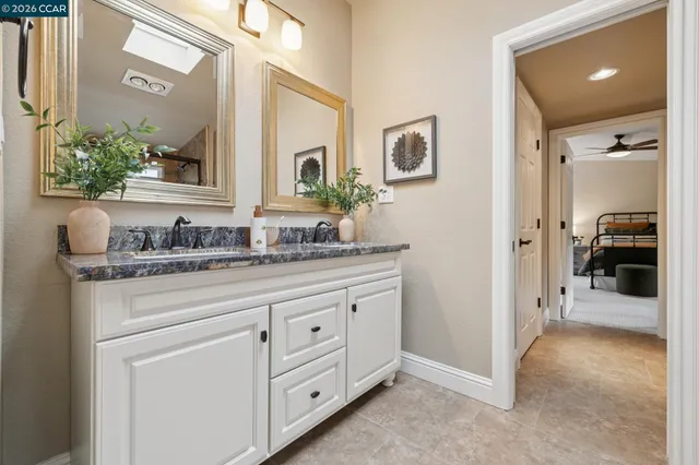 a bathroom with a granite countertop sink mirror vanity and toilet