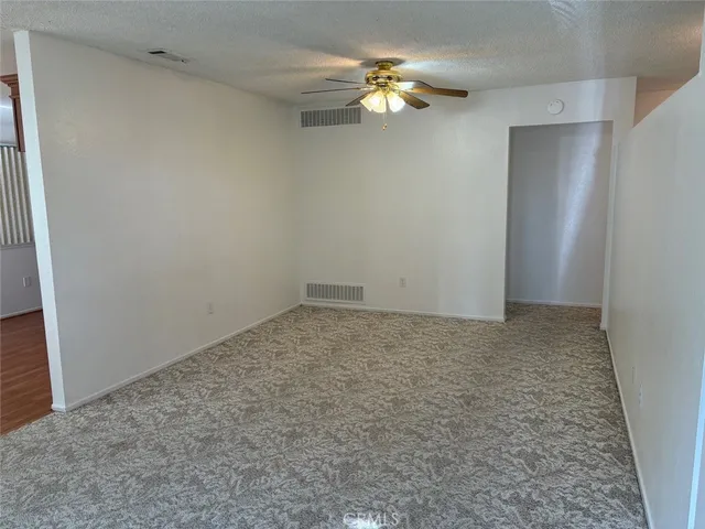 an empty room with a chandelier fan and closet