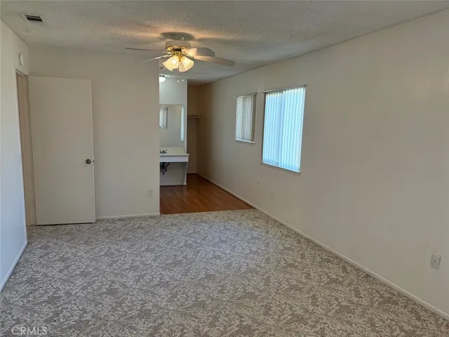 an empty room with windows and fan