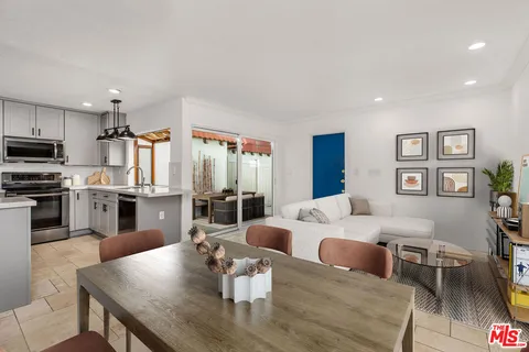 a living room with stainless steel appliances furniture a rug and a kitchen view