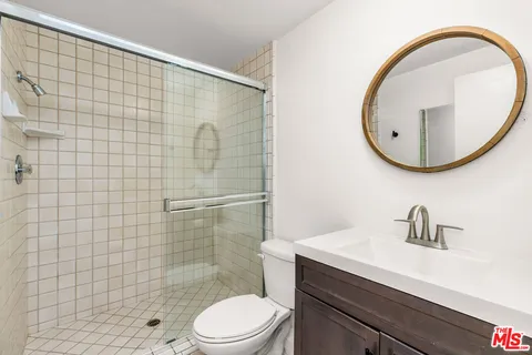 a bathroom with a toilet a sink a mirror and shower