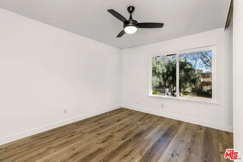 a view of empty room with wooden floor and fan