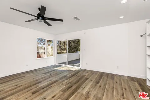 a view of a room with wooden floor and a ceiling fan