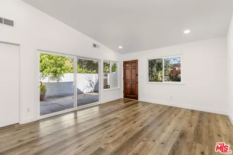 a view of an empty room with wooden floor and a window