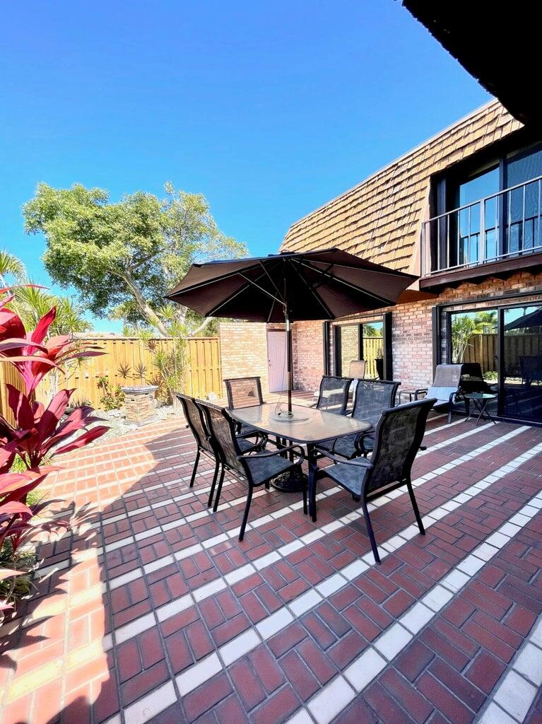 1420 Ocean Way, Unit 32C Jupiter, FL 33477 - Photo 2 of 22 a backyard of a house with table and chairs