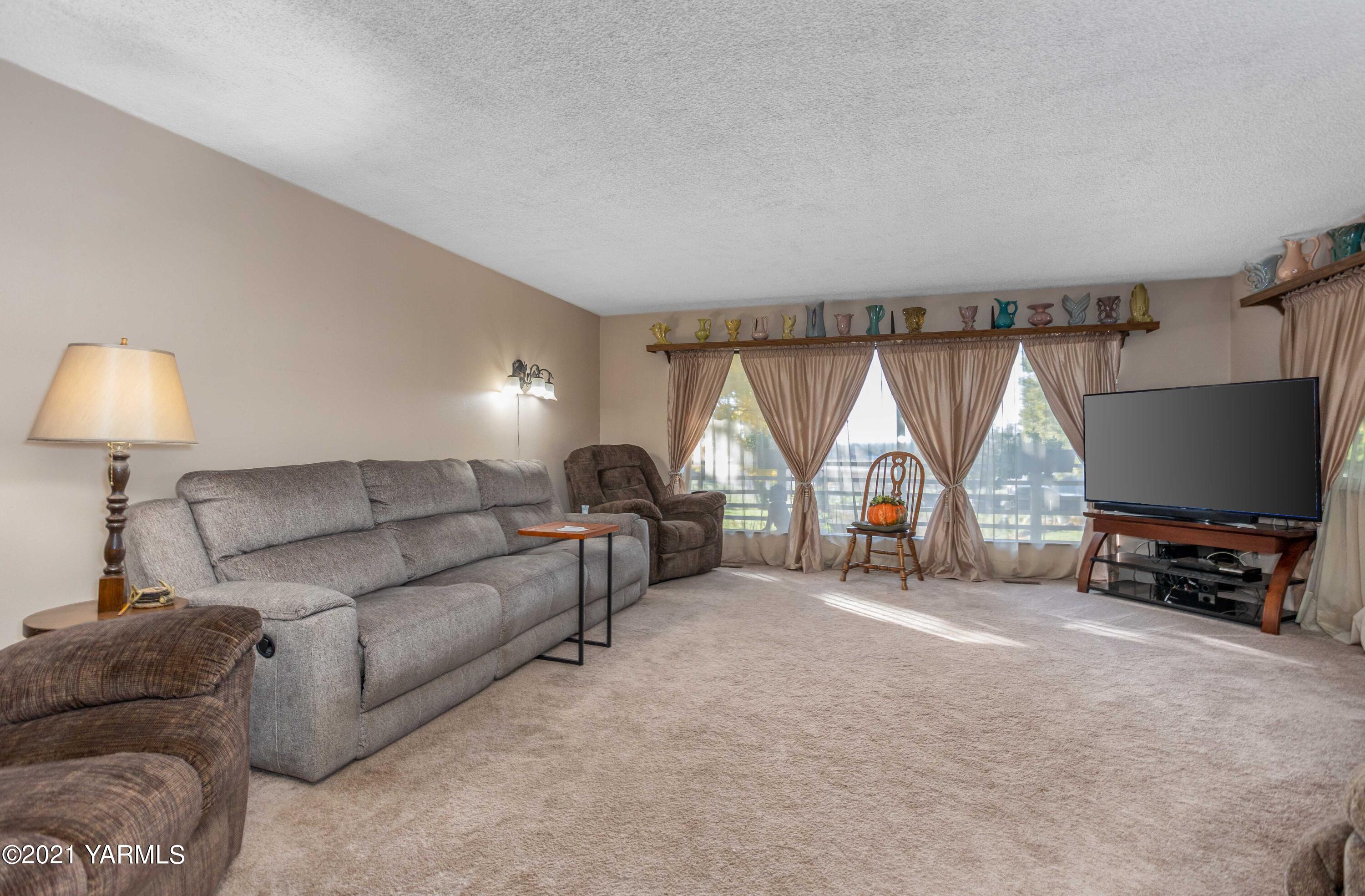 800 Blaine Road Granger, WA 98932 - Photo 6 of 43 a living room with furniture a large window and a flat screen tv