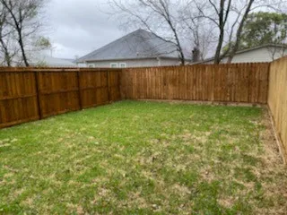 a view of backyard with wooden fence