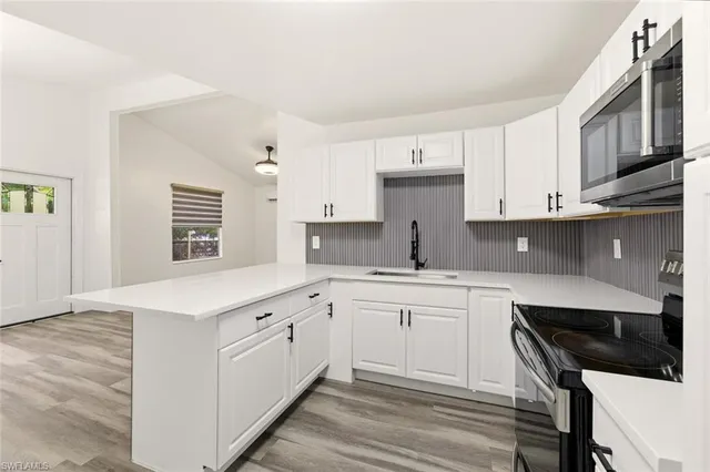 a kitchen with stainless steel appliances granite countertop a stove top oven a sink a microwave and cabinets