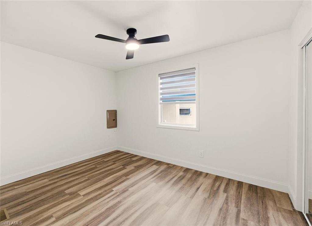 5317 Dixie Drive Naples, FL 34113 - Photo 15 of 36 an empty room with wooden floor ceiling fan and windows