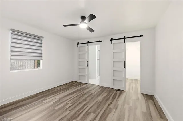 an empty room with wooden floor ceiling fan and windows