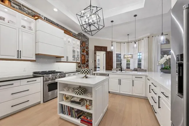 a kitchen with stainless steel appliances granite countertop a refrigerator a stove a sink dishwasher and white cabinets with wooden floor