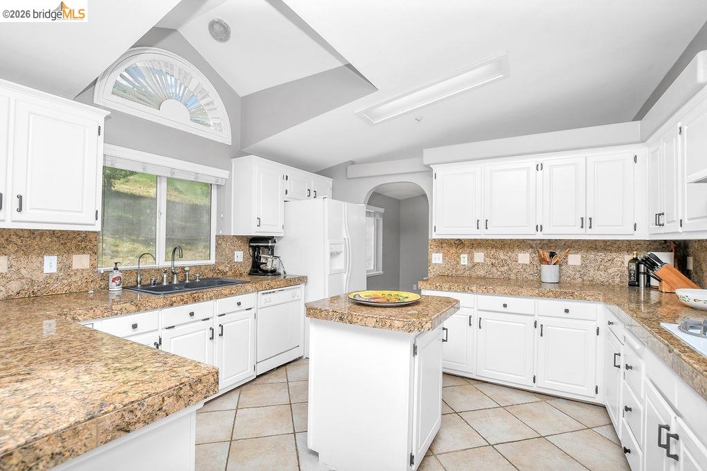 4229 Briones Valley Road Brentwood, CA 94513 - Photo 21 of 37 Kitchen featuring tile counters, white cabinetry, vaulted ceiling, and decorative backsplash