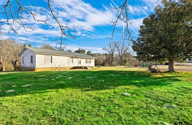 a view of a big yard with plants and large trees