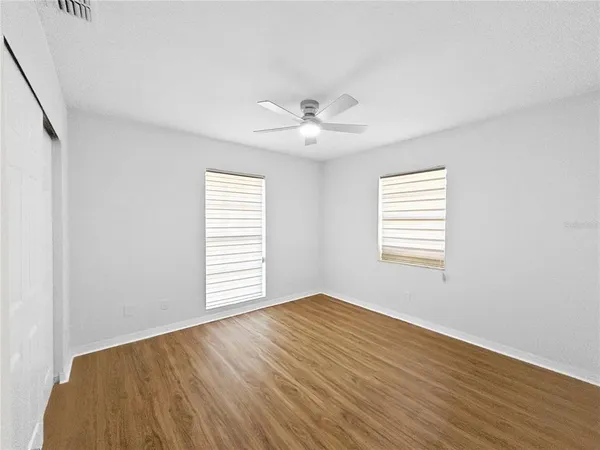 a view of a room with a ceiling fan and wooden floor