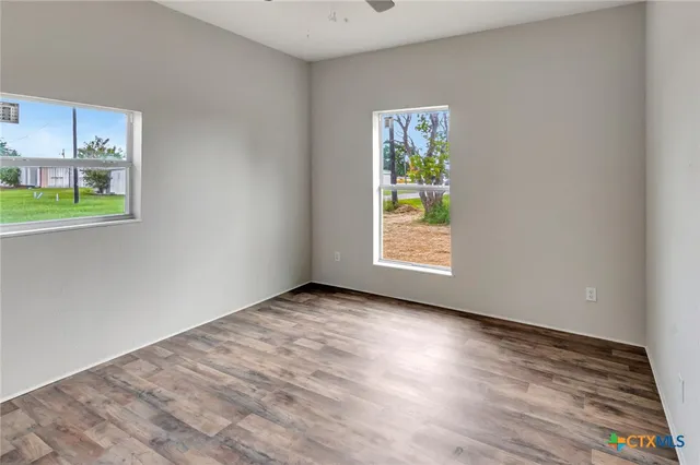 an empty room with windows and wooden floor
