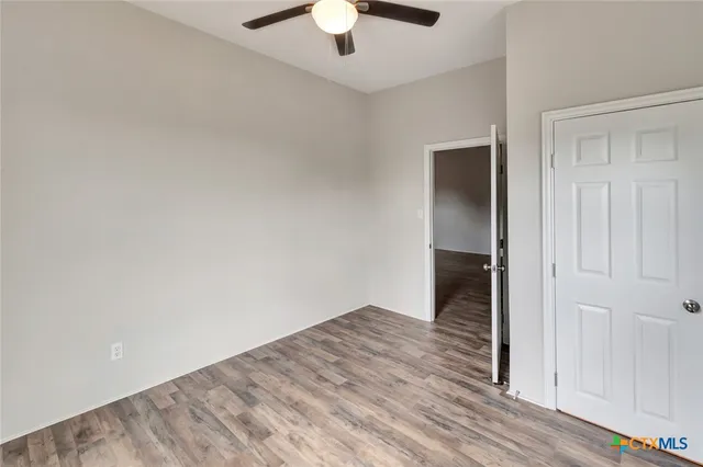an empty room with wooden floor chandelier fan and closet