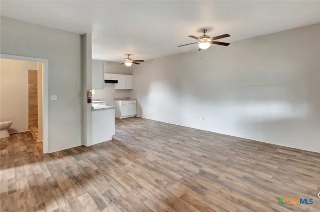 a view of a room with wooden floor and a ceiling fan