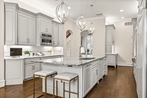 a kitchen with stainless steel appliances kitchen island granite countertop a table chairs in it and wooden floors
