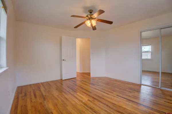a view of empty room with wooden floor and fan