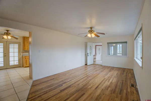 a view of empty room with wooden floor and fan
