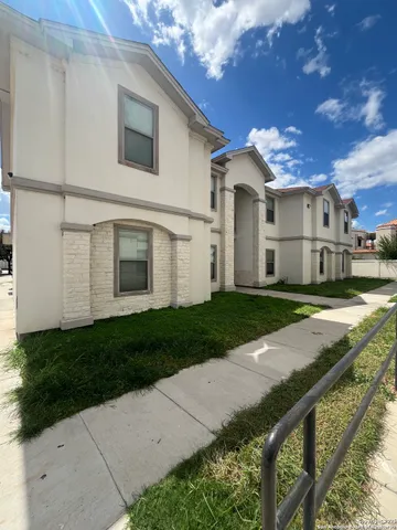 a view of a white house with a yard and large tree