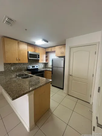 a kitchen with stainless steel appliances granite countertop a refrigerator a stove a sink and a microwave