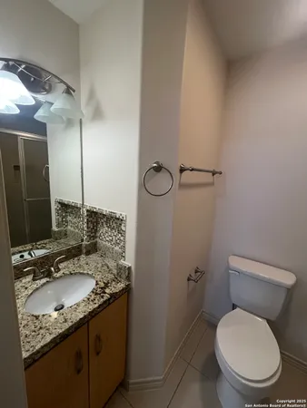 a bathroom with a granite countertop toilet sink and mirror