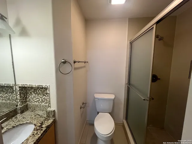 a bathroom with a granite countertop toilet and a shower