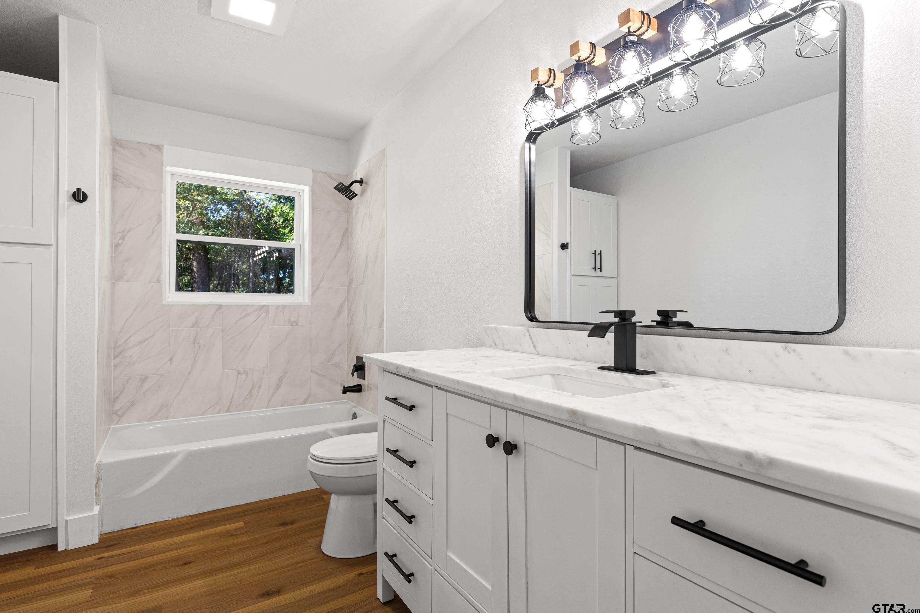 1907 Beth Drive Longview, TX 75605 - Photo 28 of 40 a bathroom with a granite countertop sink a toilet and bathtub