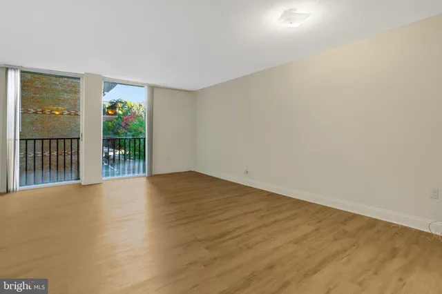 a view of an empty room with wooden floor and a window