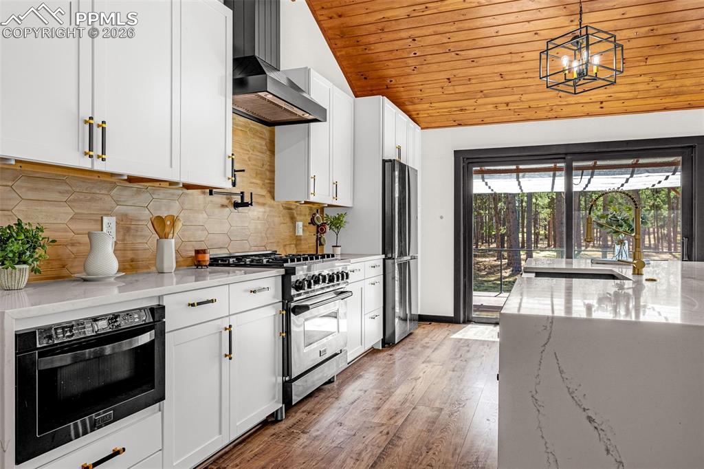 15520 Bar X Road Colorado Springs, CO 80908 - Photo 12 of 50 a kitchen with stainless steel appliances granite countertop a stove and white cabinets