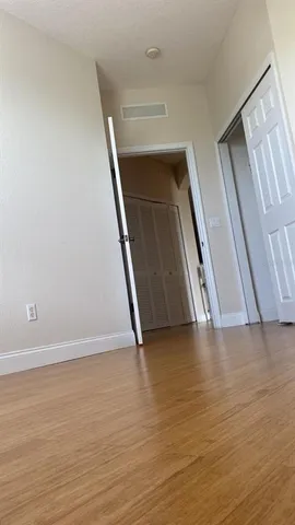 a view of an empty room with wooden floor and stairs