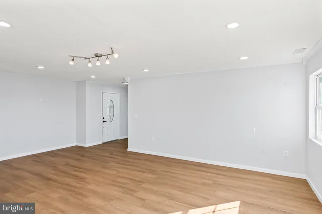 a kitchen with stainless steel appliances granite countertop white cabinets a sink a stove a microwave and wooden floors