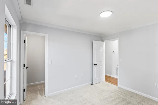a view of an empty room with window and closet area
